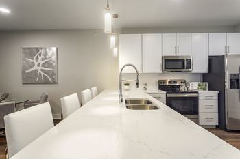A kitchen with a large white counter top and a sink